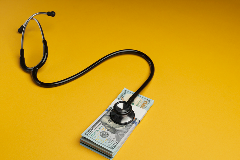A stethoscope resting on a stack of 100-dollar bills